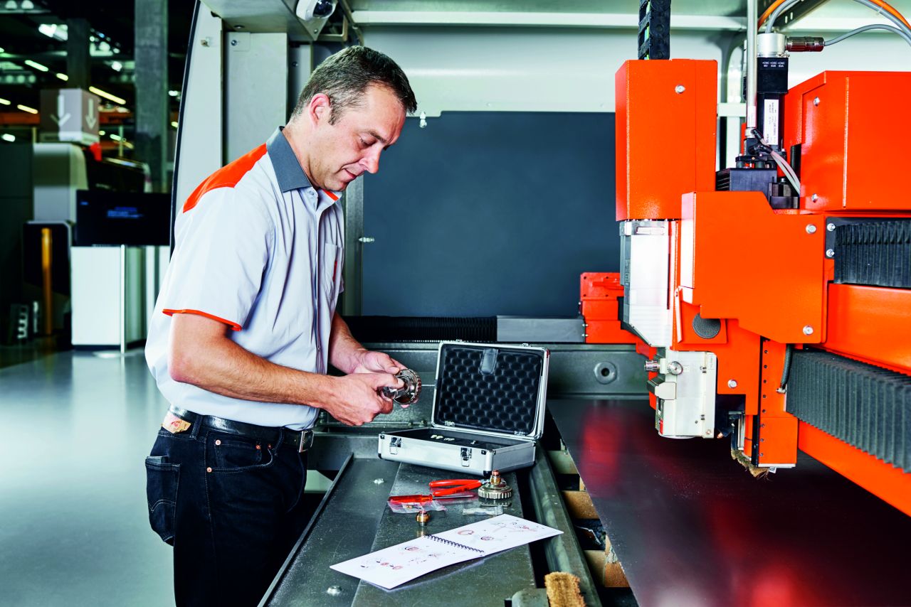 Man with toolbox examines a fiber laser machine 