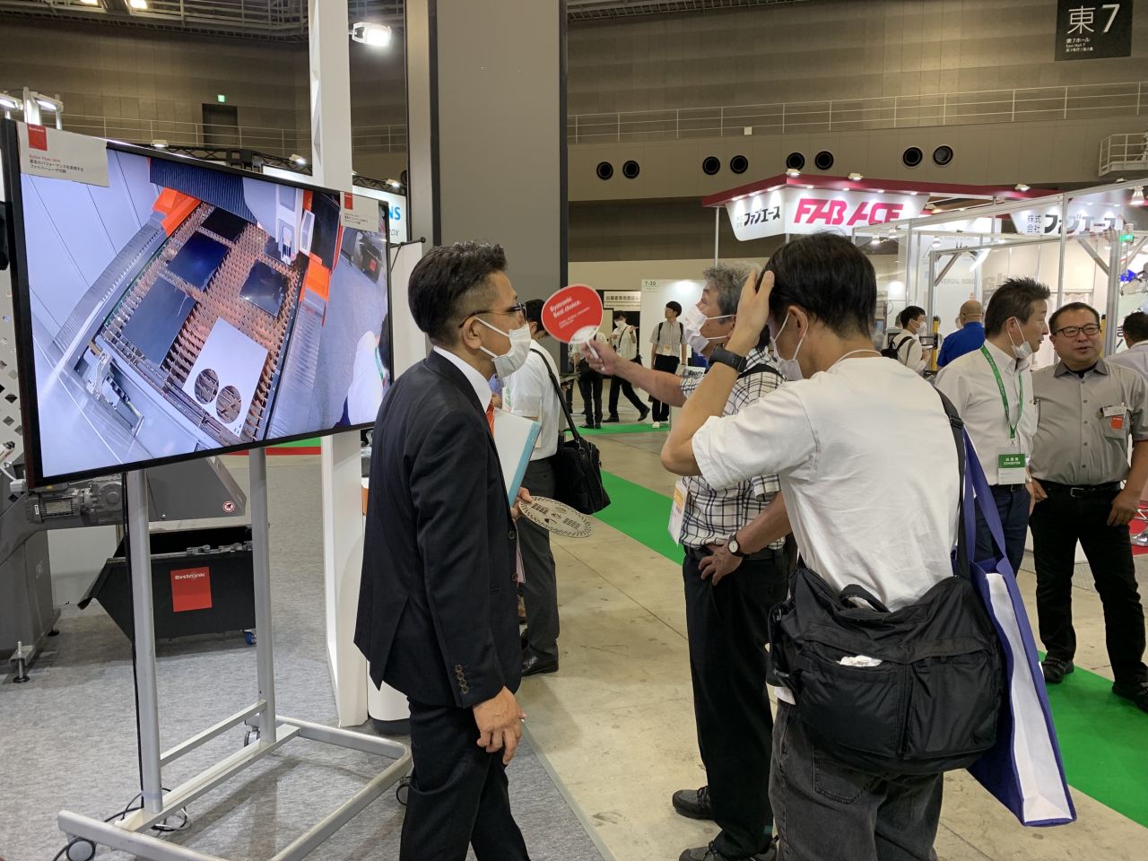 people looking at screen to look inside a laser cutting machine