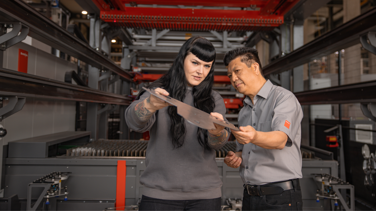 Bystronic employees providing after sales and service by reviewing a cut sheet metal part.