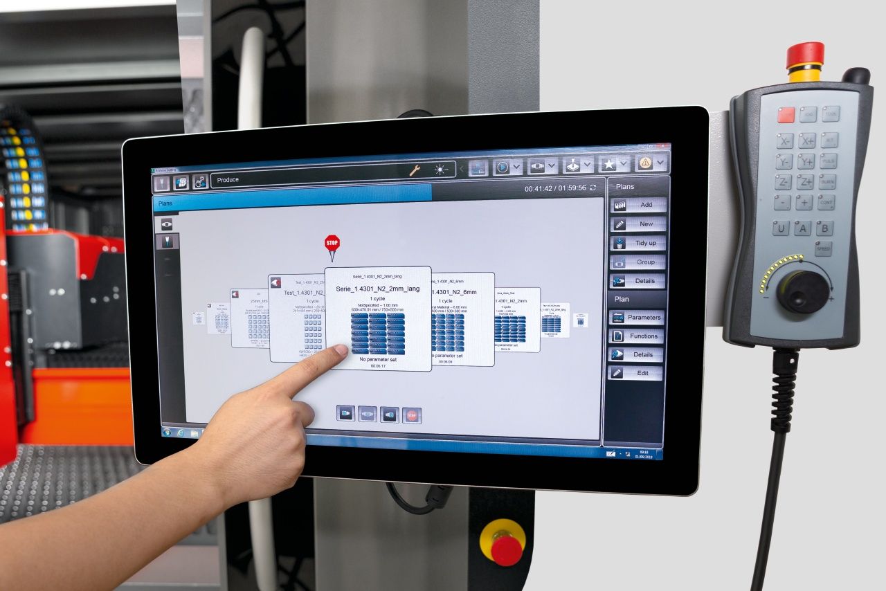 Person operating laser cutter on a touchscreen to process metal