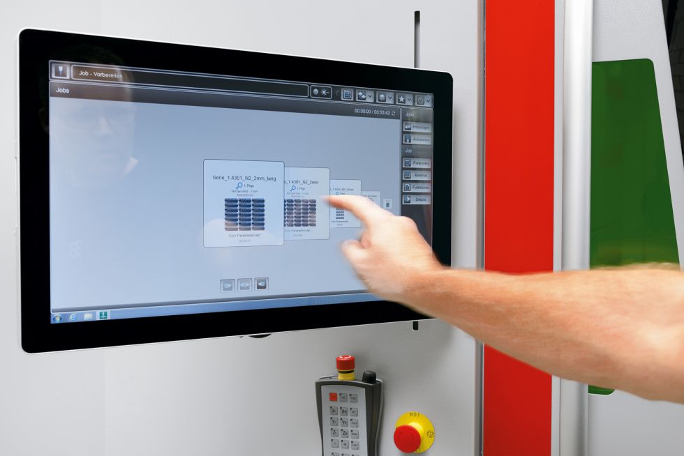 Man operates fiber laser cutting machine on touchscreen