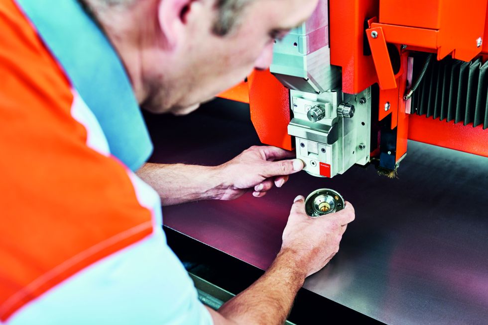 Service technician repairs cutting head of fiber laser machine