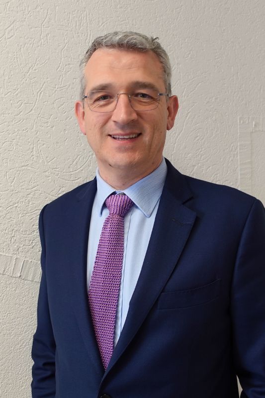 smiling man with short gray hair and blue suit