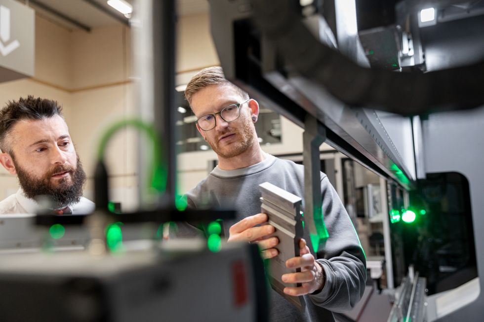 two main in front of a bending machine, one is explaining