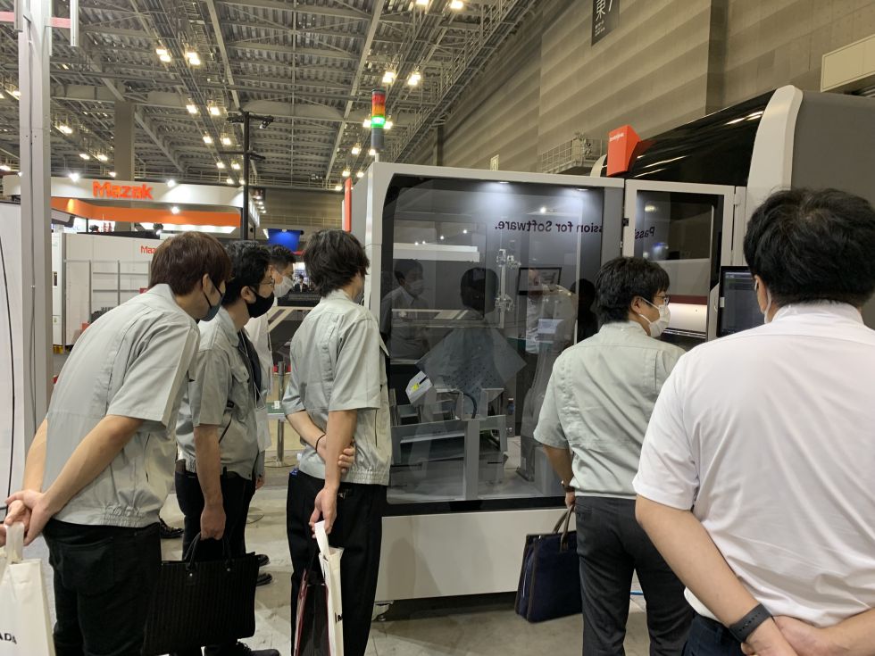 people looking at a small metal bending robot from Bystronic