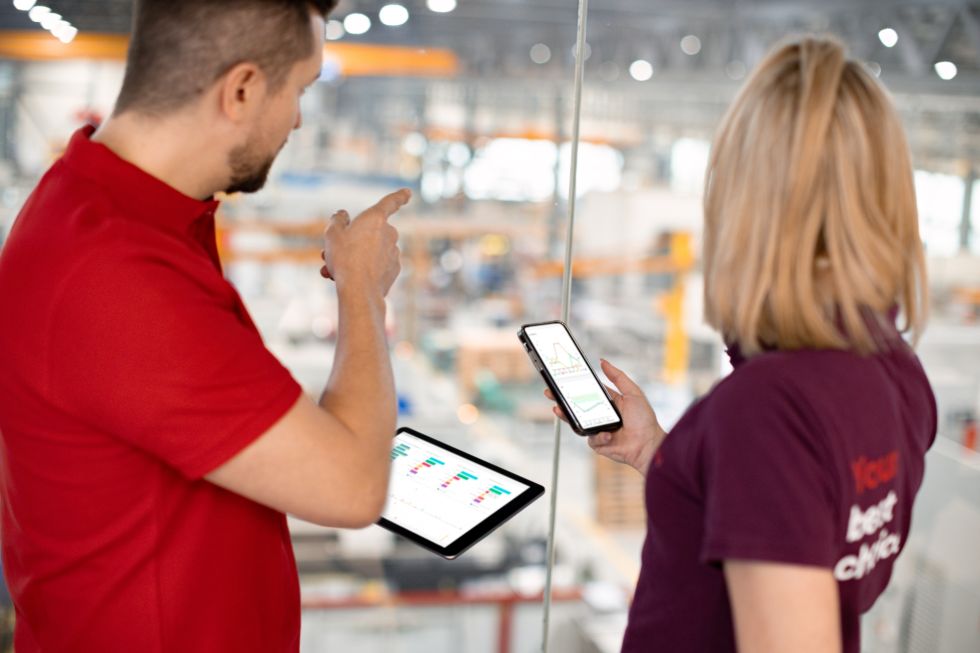 woman and man comparing data on a phone and a tablet