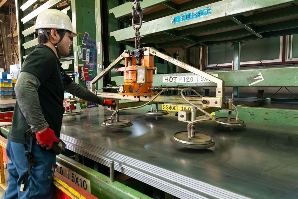Large metal sheets are lifted onto the cutting machines using suction cups