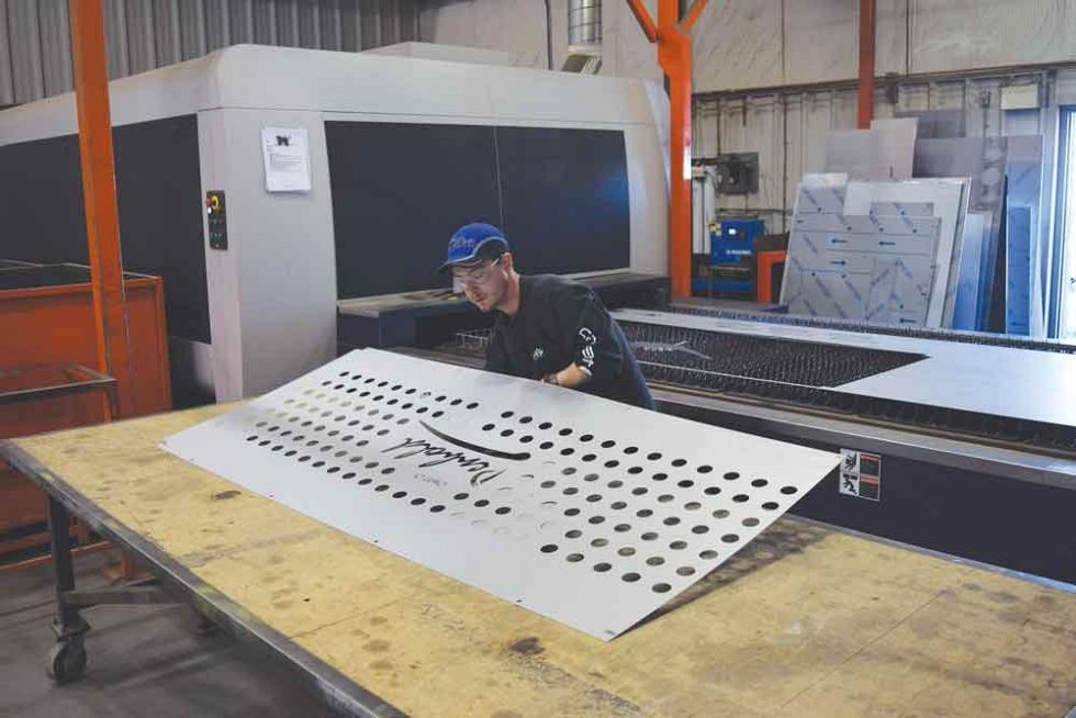 The laser operator removing a cut sheet from the fiber laser table. The kit he cut on the sheet in this case is for a trash receptacle for a local community. With the fiber laser, Hawk was able to design this kit in such a way that it can be assembly more easily.